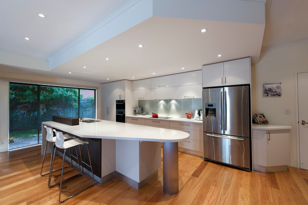Design ideas for a mid-sized contemporary galley eat-in kitchen in Perth with an integrated sink, flat-panel cabinets, quartz benchtops, metallic splashback, glass sheet splashback, stainless steel appliances, light hardwood floors and with island.