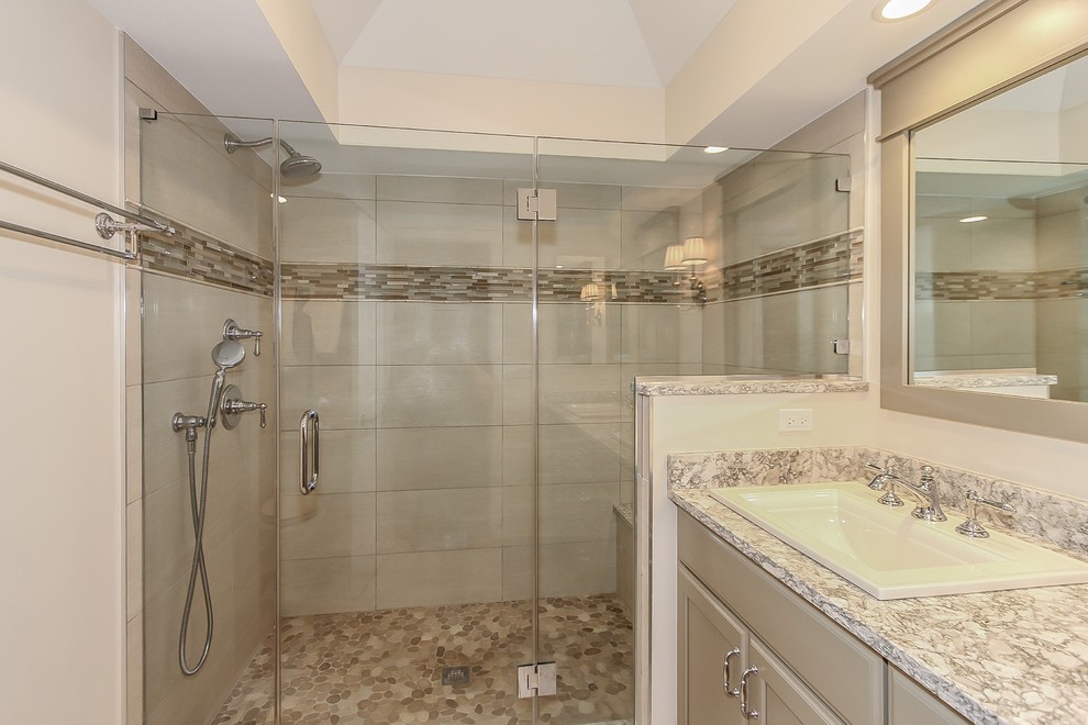 Inspiration for a large transitional master bathroom in Chicago with recessed-panel cabinets, beige cabinets, an alcove shower, a two-piece toilet, beige tile, ceramic tile, beige walls, ceramic floors, a drop-in sink, engineered quartz benchtops, beige floor, a hinged shower door and beige benchtops.