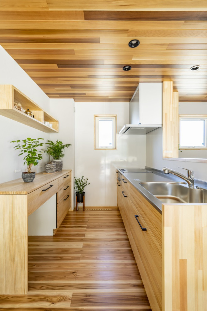 Inspiration for a small modern galley open plan kitchen in Other with an integrated sink, beaded inset cabinets, brown cabinets, stainless steel benchtops, white splashback, light hardwood floors, brown floor, brown benchtop and timber.