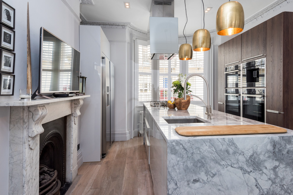 Inspiration for a mid-sized traditional galley open plan kitchen in Sussex with an undermount sink, flat-panel cabinets, grey cabinets, granite benchtops, panelled appliances, medium hardwood floors and with island.