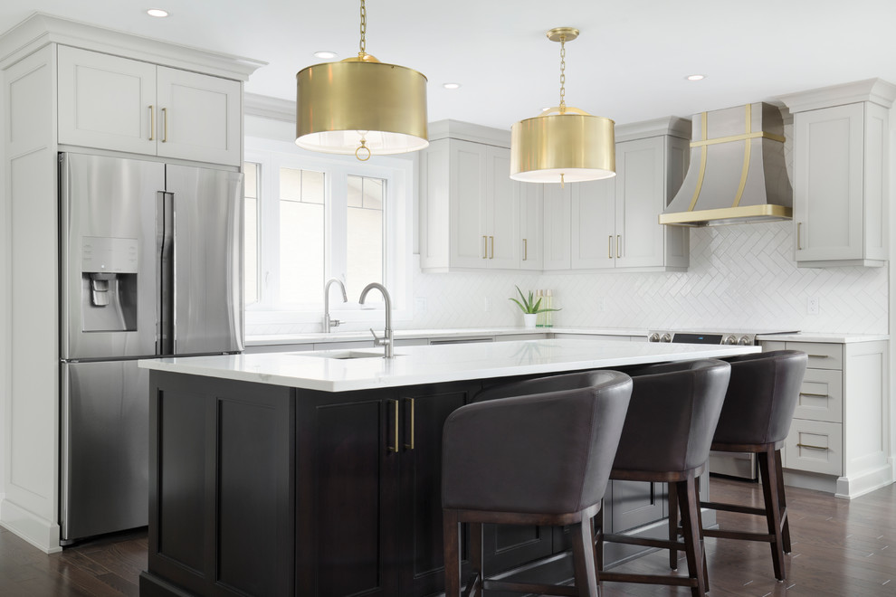 Kitchen - transitional l-shaped kitchen idea in Calgary with shaker cabinets, gray cabinets, quartz countertops, white backsplash, porcelain backsplash, stainless steel appliances and an island