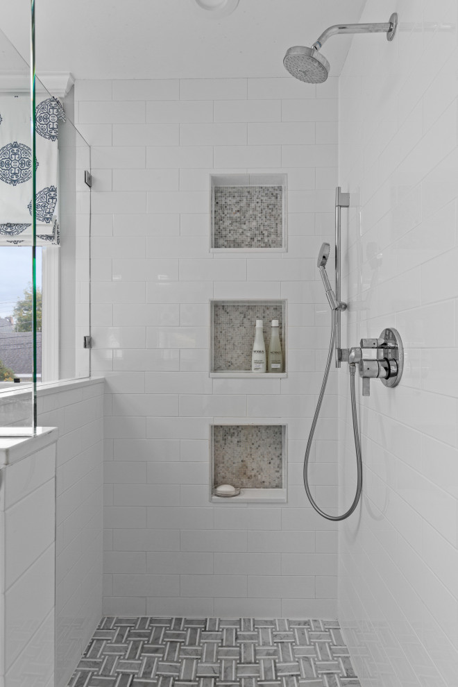 This is an example of a mid-sized transitional master bathroom in Chicago with shaker cabinets, white cabinets, a freestanding tub, a corner shower, a one-piece toilet, white tile, subway tile, grey walls, mosaic tile floors, a wall-mount sink, engineered quartz benchtops, grey floor, a hinged shower door, white benchtops, a niche, a double vanity and a freestanding vanity.