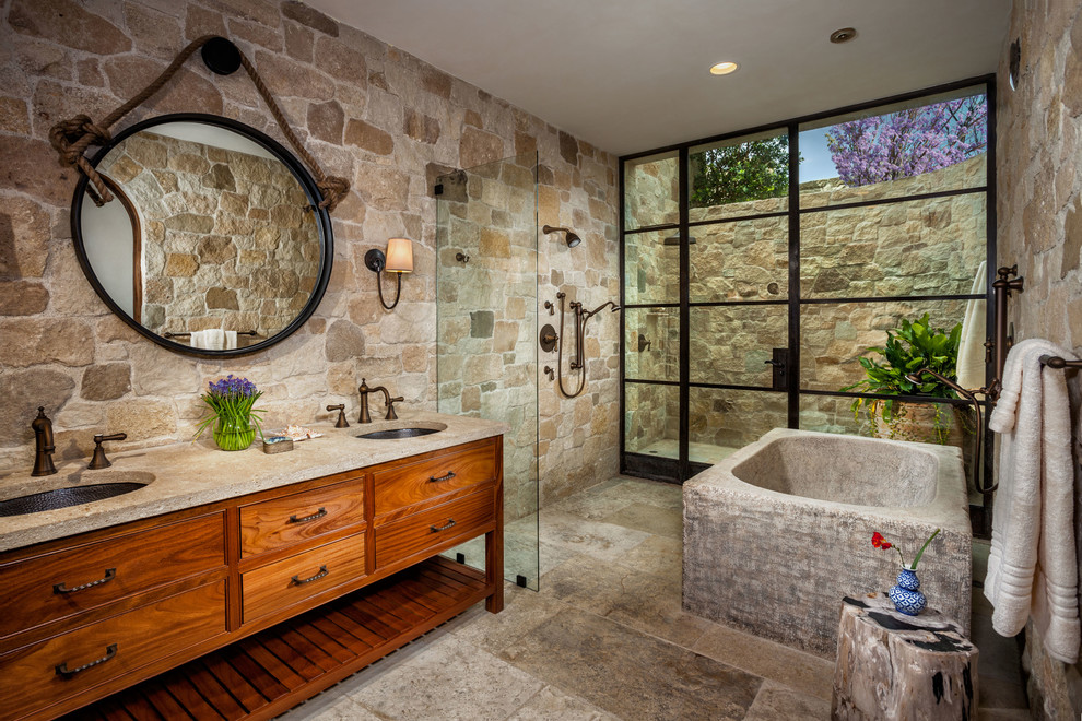 Large mediterranean master bathroom in Orange County with medium wood cabinets, an open shower, beige tile, beige walls, an undermount sink, beige floor, an open shower, a freestanding tub, stone tile and flat-panel cabinets.