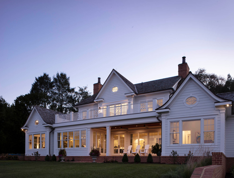 Cette image montre une grande façade de maison blanche traditionnelle à un étage avec un toit mixte et un toit marron.