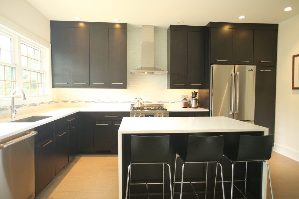 Kitchen - transitional l-shaped ceramic tile kitchen idea in Chicago with dark wood cabinets, quartz countertops, white backsplash, glass tile backsplash, an undermount sink, flat-panel cabinets, stainless steel appliances and an island