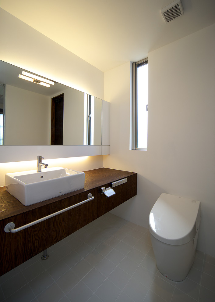 Design ideas for a small modern powder room in Other with furniture-like cabinets, white cabinets, a one-piece toilet, white walls, porcelain floors, a vessel sink, wood benchtops and white floor.