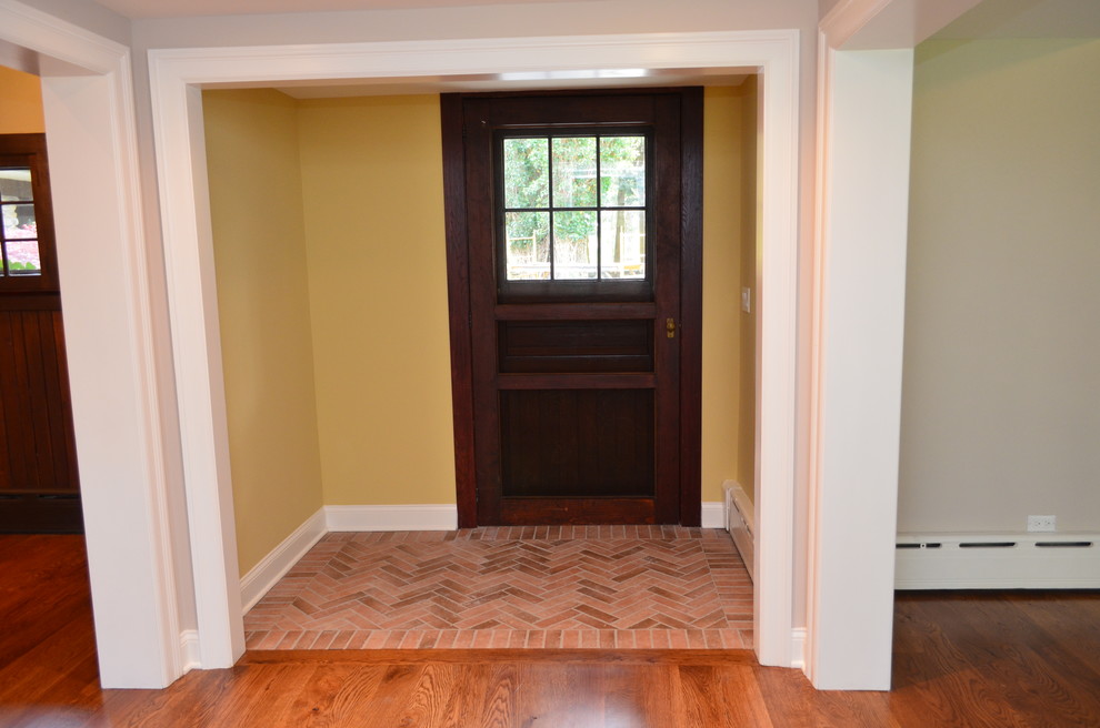 Photo of a mid-sized country foyer in Other with yellow walls, brick floors, a single front door and a dark wood front door.