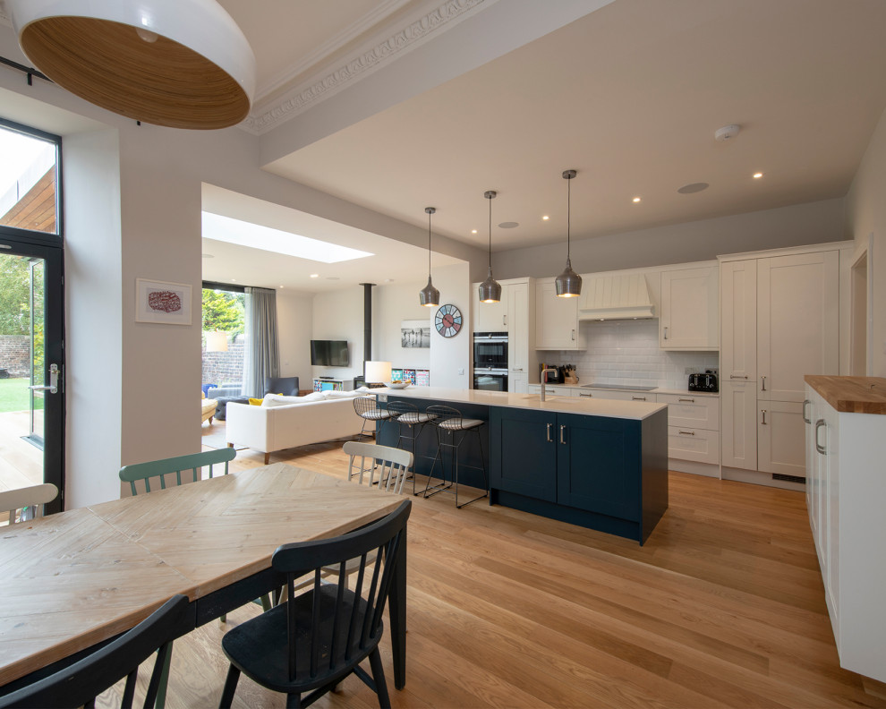 This is an example of a large traditional open plan kitchen in Edinburgh with shaker cabinets, quartzite benchtops, white splashback, subway tile splashback, panelled appliances, with island and multi-coloured benchtop.