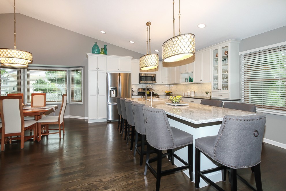 Inspiration for a mid-sized transitional l-shaped dark wood floor and brown floor eat-in kitchen remodel in Chicago with flat-panel cabinets, white cabinets, quartz countertops, beige backsplash, stone tile backsplash, stainless steel appliances, an island and a single-bowl sink