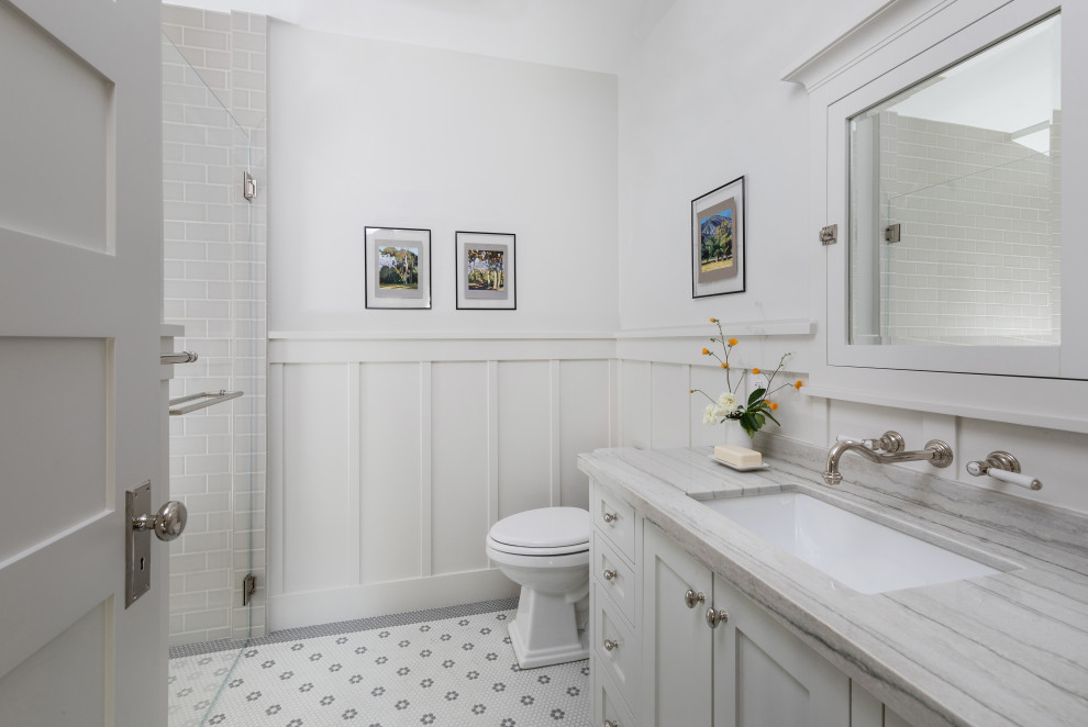 ロサンゼルスにある高級な中くらいなトラディショナルスタイルのおしゃれなバスルーム (浴槽なし) (シェーカースタイル扉のキャビネット、白いキャビネット、バリアフリー、一体型トイレ	、グレーのタイル、セラミックタイル、白い壁、モザイクタイル、アンダーカウンター洗面器、珪岩の洗面台、グレーの床、開き戸のシャワー、グレーの洗面カウンター、洗面台1つ、造り付け洗面台、羽目板の壁) の写真
