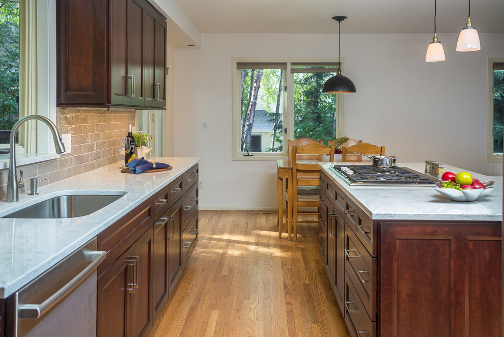 Inspiration for a mid-sized transitional l-shaped light wood floor open concept kitchen remodel with an undermount sink, recessed-panel cabinets, dark wood cabinets, quartz countertops, gray backsplash, subway tile backsplash, stainless steel appliances and an island