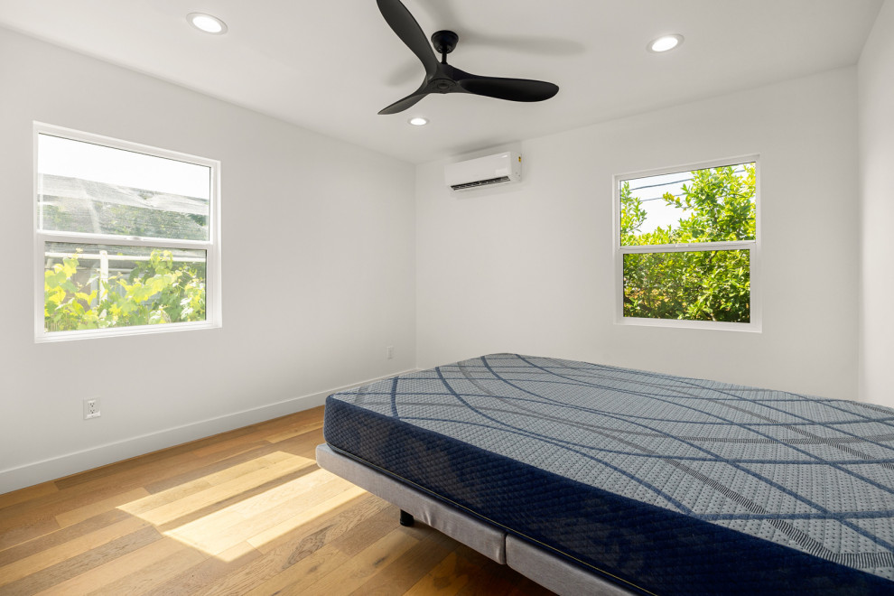На фото: хозяйская спальня среднего размера в современном стиле с белыми стенами, светлым паркетным полом и коричневым полом