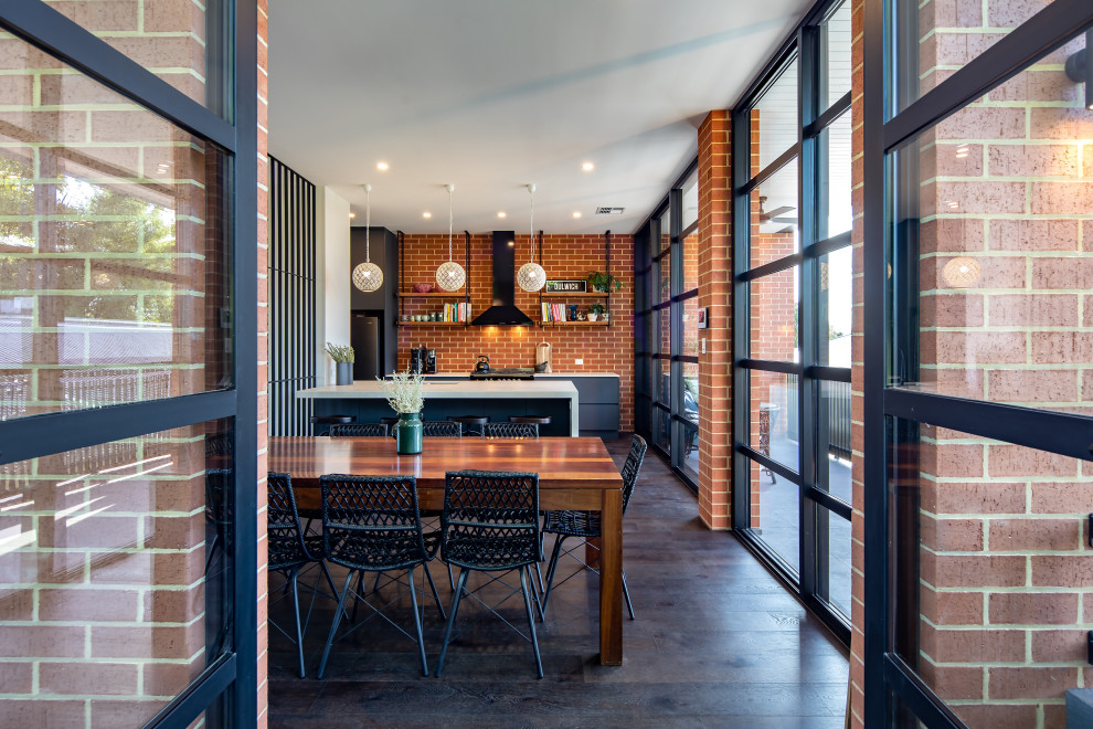 Große, Zweizeilige Moderne Wohnküche mit flächenbündigen Schrankfronten, grauen Schränken, Küchenrückwand in Rot, Rückwand aus Backstein, dunklem Holzboden, Kücheninsel, braunem Boden und weißer Arbeitsplatte in Adelaide