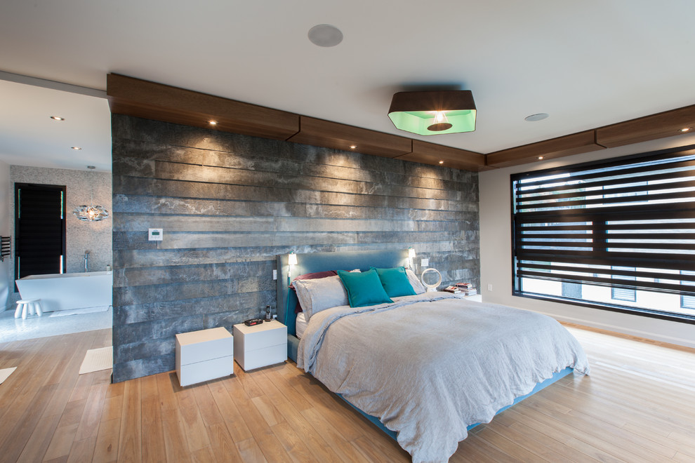 This is an example of a large contemporary master bedroom in Montreal with white walls and light hardwood floors.