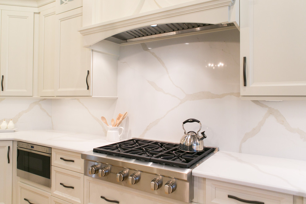 Inspiration for a mid-sized transitional u-shaped open concept kitchen remodel in Orlando with recessed-panel cabinets, white cabinets, quartzite countertops, white backsplash, stone slab backsplash, stainless steel appliances and a peninsula