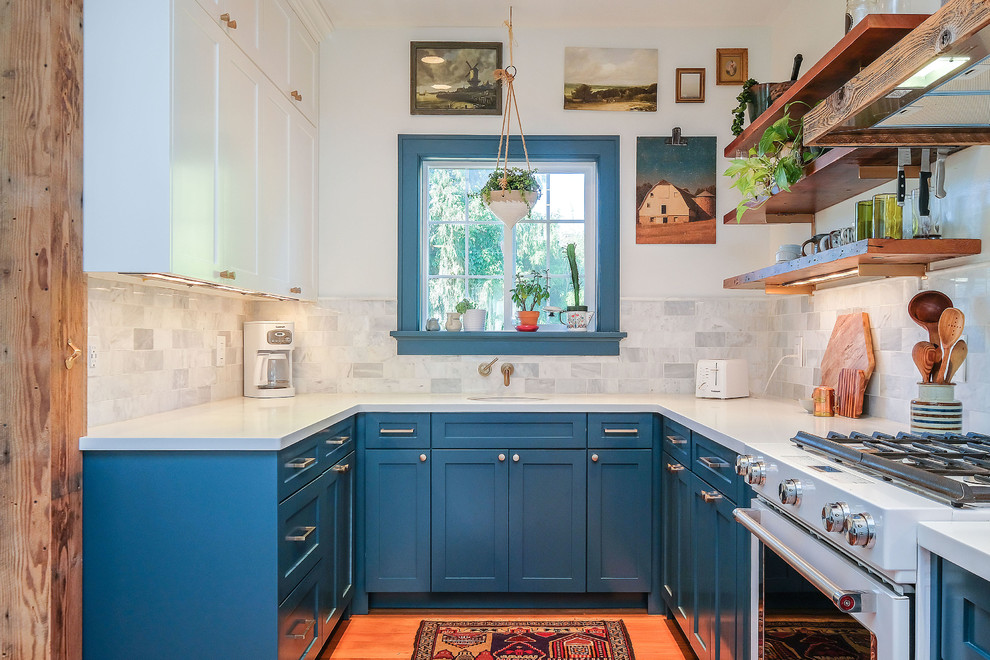 Design ideas for a transitional u-shaped kitchen in Portland with shaker cabinets, blue cabinets, quartzite benchtops, porcelain splashback, light hardwood floors and a peninsula.