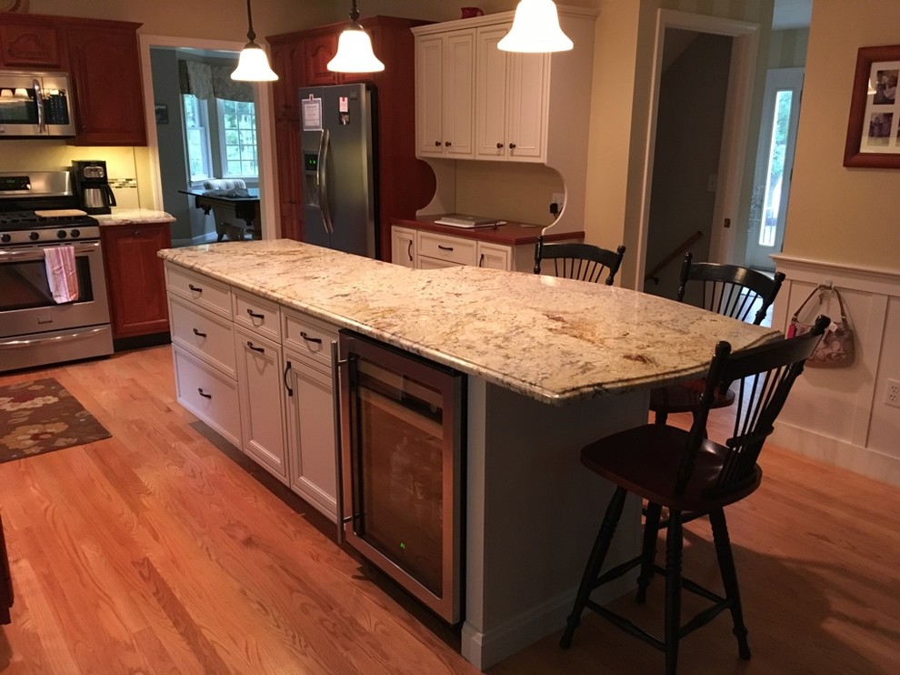 Example of a transitional u-shaped light wood floor eat-in kitchen design in Boston with an undermount sink, raised-panel cabinets, granite countertops, subway tile backsplash, stainless steel appliances and an island