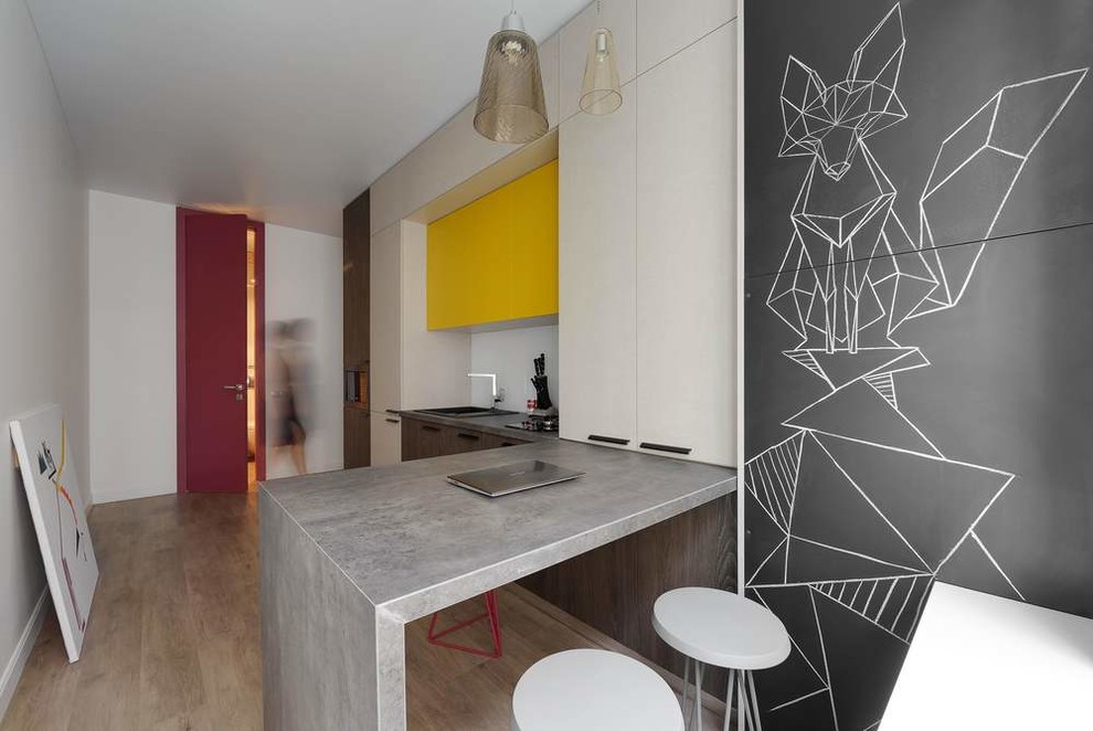 Photo of a small contemporary single-wall eat-in kitchen in Other with an undermount sink, flat-panel cabinets, yellow cabinets, quartzite benchtops, white splashback, glass tile splashback, coloured appliances, vinyl floors, a peninsula and brown floor.