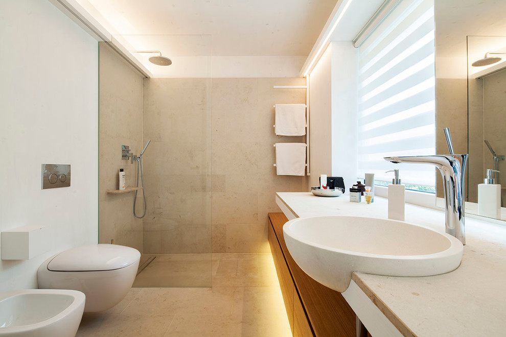 Inspiration for a mid-sized mediterranean bathroom in Cologne with flat-panel cabinets, medium wood cabinets, a curbless shower, a two-piece toilet, white walls, travertine floors, a drop-in sink and an open shower.