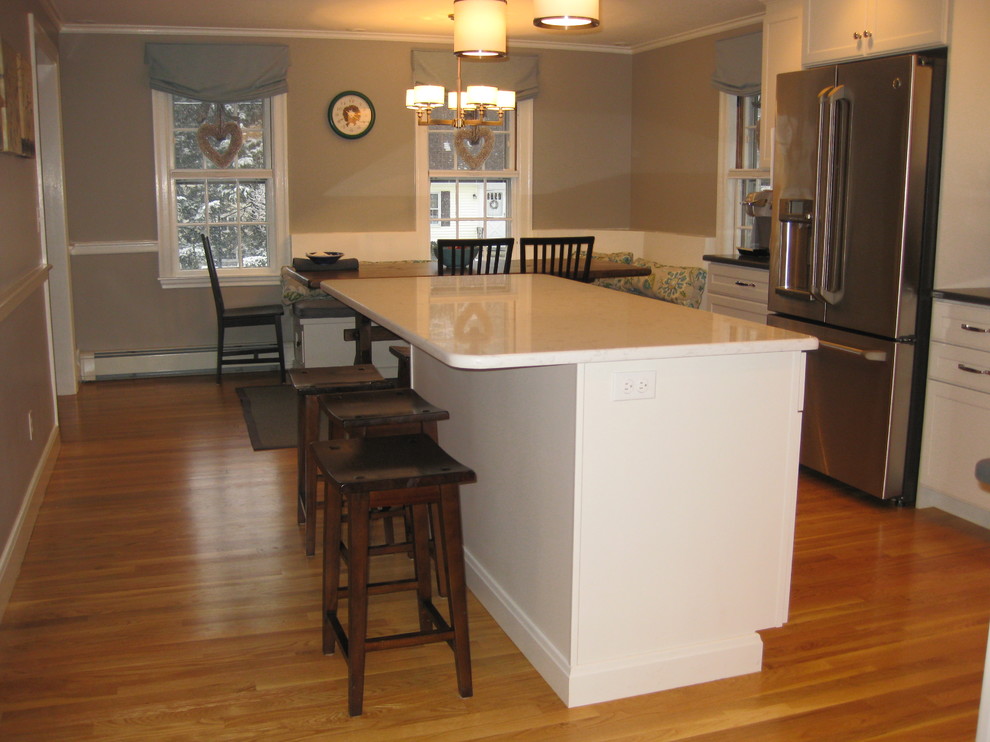 Transitional l-shaped medium tone wood floor eat-in kitchen photo in Boston with an undermount sink, white cabinets, quartz countertops, stainless steel appliances, an island, shaker cabinets, green backsplash, subway tile backsplash and black countertops