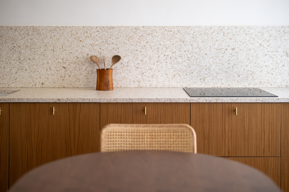 Inspiration for a mid-sized transitional l-shaped eat-in kitchen in Nice with an undermount sink, light wood cabinets, terrazzo benchtops, pink splashback, black appliances, medium hardwood floors, no island, brown floor and pink benchtop.