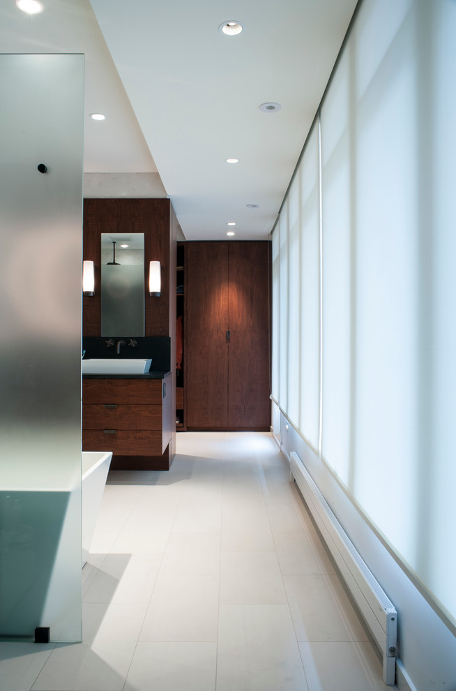 Photo of a mid-sized contemporary master bathroom in DC Metro with a vessel sink, flat-panel cabinets, medium wood cabinets, a freestanding tub, a curbless shower, beige tile, porcelain tile, white walls, porcelain floors and soapstone benchtops.