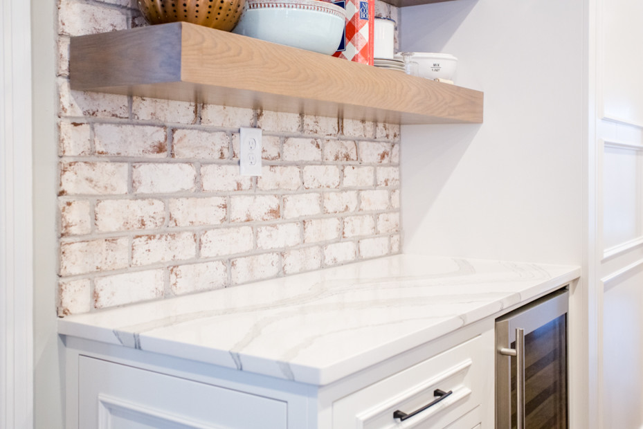 Eat-in kitchen - large transitional u-shaped medium tone wood floor and brown floor eat-in kitchen idea in Atlanta with a farmhouse sink, raised-panel cabinets, white cabinets, quartz countertops, white backsplash, brick backsplash, stainless steel appliances, an island and white countertops