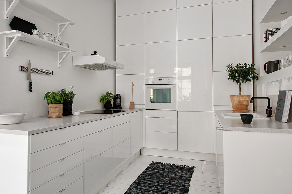Inspiration for a mid-sized scandinavian galley kitchen in Gothenburg with a single-bowl sink, flat-panel cabinets, white cabinets, white appliances, painted wood floors and no island.