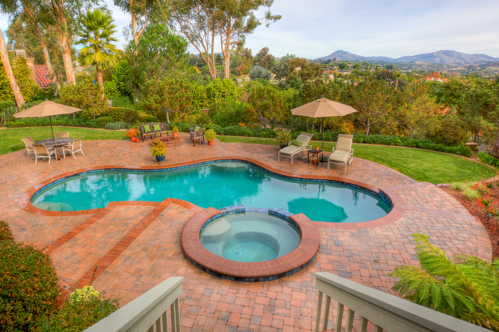 Photo of a large contemporary backyard custom-shaped lap pool in San Diego with a hot tub and brick pavers.