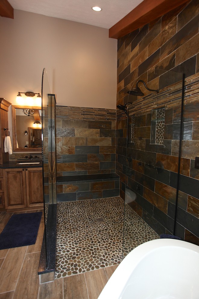 Example of a large mountain style master slate tile brown floor freestanding bathtub design in Indianapolis with brown cabinets, beige walls and an undermount sink