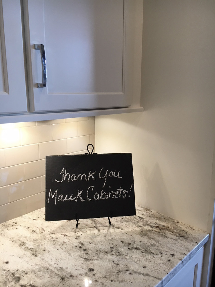 Example of a large transitional l-shaped dark wood floor and brown floor eat-in kitchen design with a farmhouse sink, recessed-panel cabinets, white cabinets, granite countertops, white backsplash, ceramic backsplash, stainless steel appliances and an island