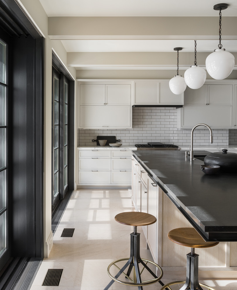 Inspiration for a mid-sized transitional limestone floor and beige floor kitchen remodel in Seattle with a single-bowl sink, shaker cabinets, gray cabinets, granite countertops, white backsplash, brick backsplash, stainless steel appliances, an island and black countertops