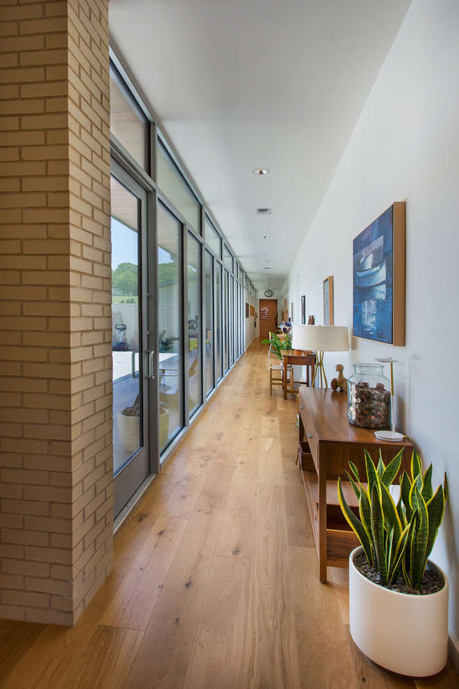 Photo of a large midcentury hallway in Dallas with beige walls, medium hardwood floors and brown floor.