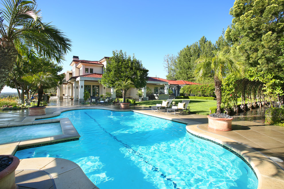 Inspiration for a mediterranean backyard concrete and custom-shaped pool remodel in Orange County
