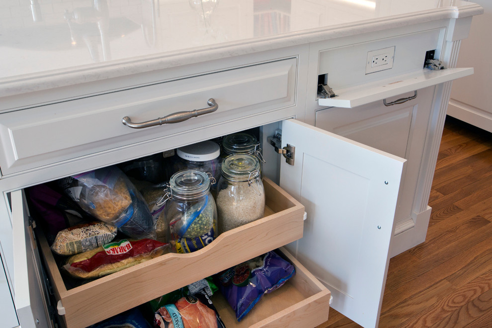 Example of a large transitional l-shaped medium tone wood floor eat-in kitchen design with a farmhouse sink, white cabinets, granite countertops, white backsplash, stainless steel appliances, an island, raised-panel cabinets and subway tile backsplash
