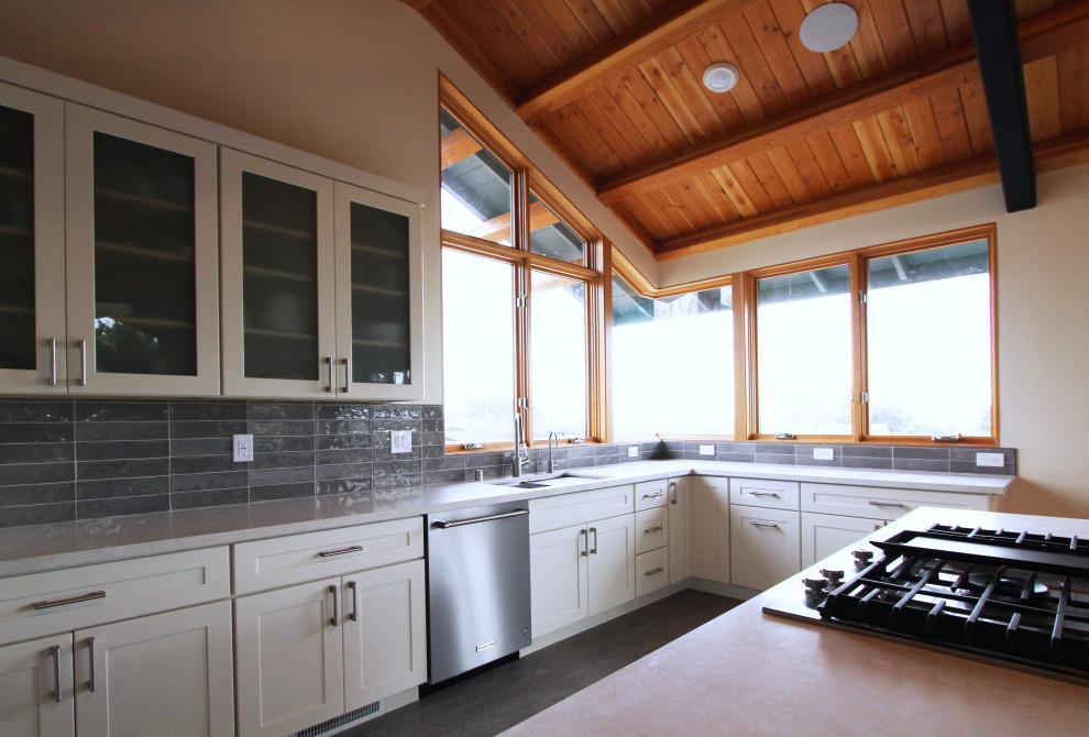 Open concept kitchen - mid-sized transitional l-shaped gray floor open concept kitchen idea with an undermount sink, shaker cabinets, white cabinets, quartz countertops, gray backsplash, ceramic backsplash, stainless steel appliances, an island and multicolored countertops