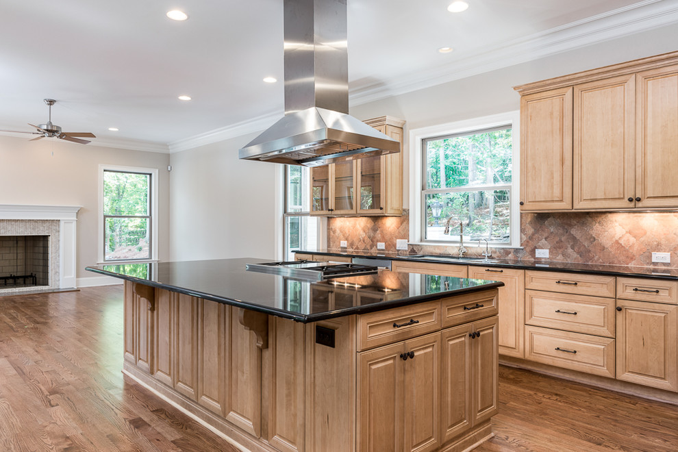 Photo of a large traditional eat-in kitchen in Raleigh with an undermount sink, raised-panel cabinets, light wood cabinets, granite benchtops, multi-coloured splashback, stainless steel appliances, light hardwood floors, with island and black benchtop.