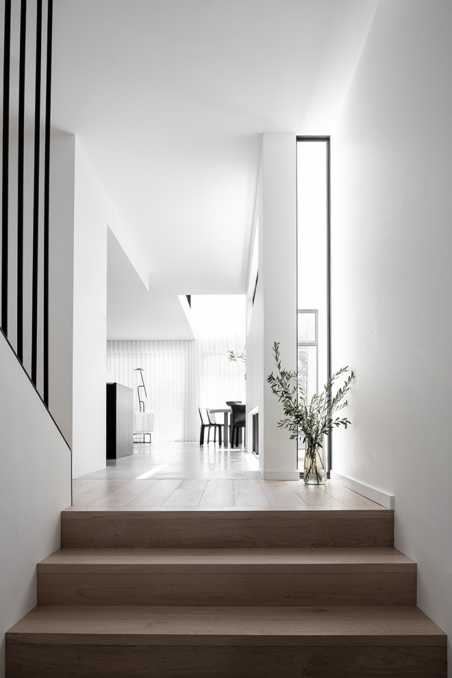 Inspiration for a large contemporary entry hall in Melbourne with white walls, light hardwood floors, a pivot front door, a glass front door and beige floor.