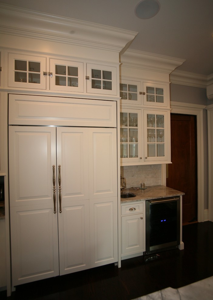 Photo of a large traditional l-shaped eat-in kitchen in New York with a farmhouse sink, beaded inset cabinets, white cabinets, quartzite benchtops, panelled appliances, dark hardwood floors and with island.