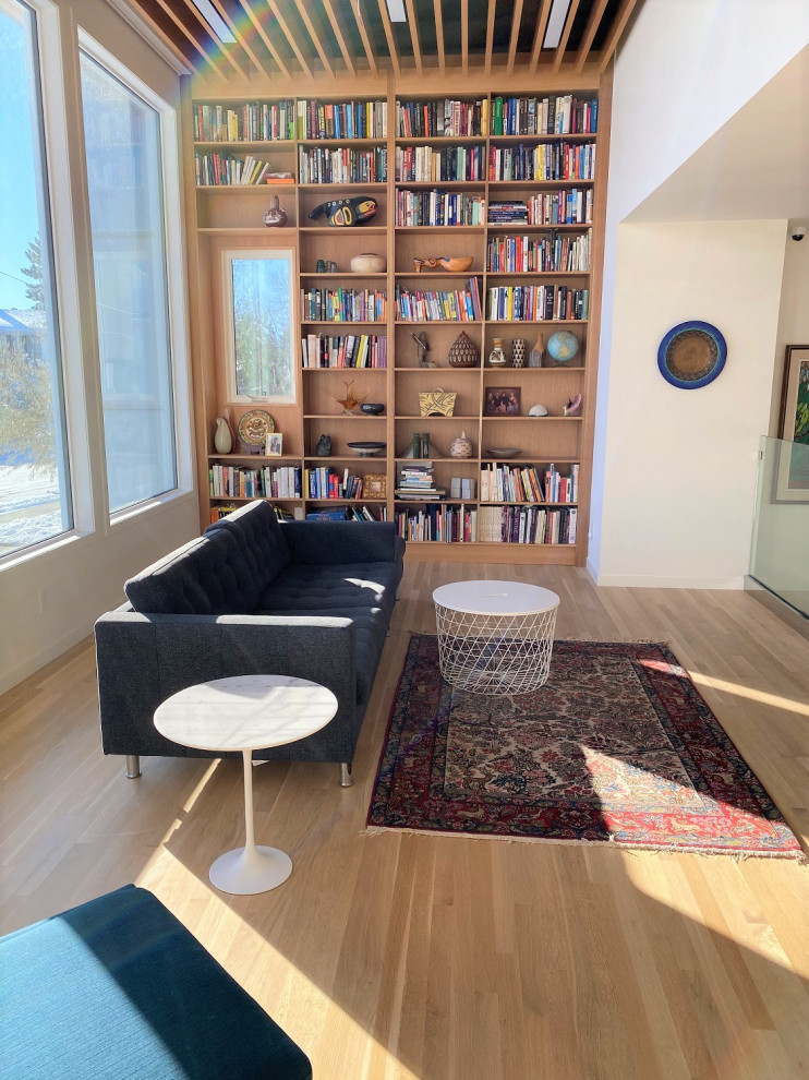 Réalisation d'un salon mansardé ou avec mezzanine minimaliste en bois de taille moyenne avec une bibliothèque ou un coin lecture, un mur blanc, parquet clair et un plafond en bois.
