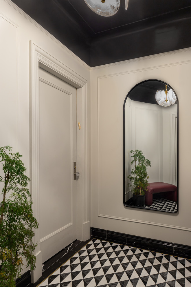 На фото: маленький вестибюль в стиле неоклассика (современная классика) с одностворчатой входной дверью, белыми стенами, полом из керамогранита, белой входной дверью, черным полом и панелями на части стены для на участке и в саду с