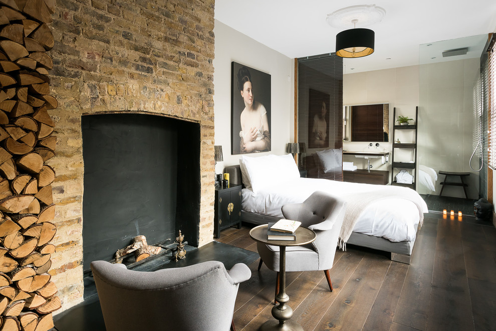 Design ideas for a mediterranean master and grey and brown bedroom in London with dark hardwood flooring, a standard fireplace, a brick fireplace surround, beige walls and brown floors.
