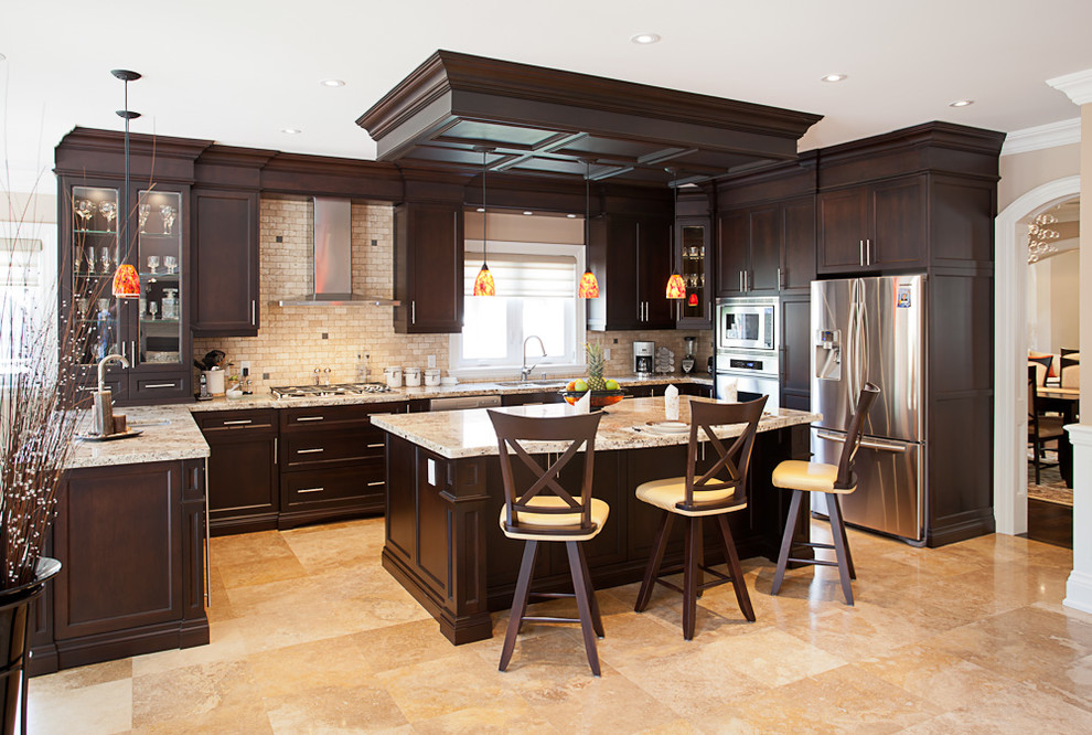 This is an example of a mid-sized traditional galley open plan kitchen in Toronto with recessed-panel cabinets, granite benchtops, beige splashback, stone tile splashback, stainless steel appliances and with island.