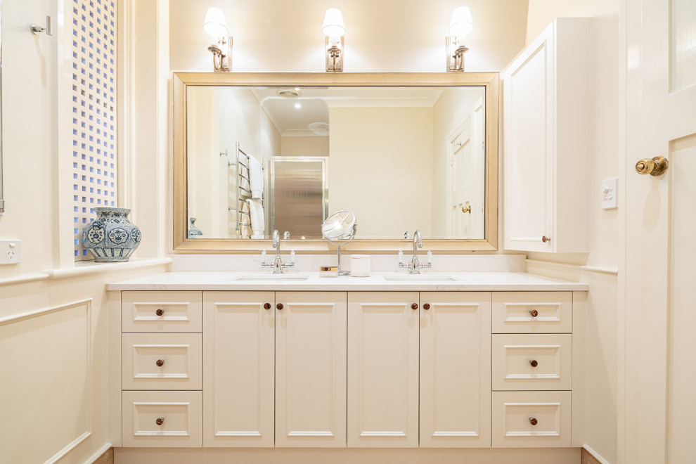 Aménagement d'une salle de bain principale classique de taille moyenne avec des portes de placard beiges, une douche d'angle, un mur beige, un lavabo encastré, un plan de toilette en marbre, un sol beige, une cabine de douche à porte battante, un plan de toilette gris, meuble double vasque et meuble-lavabo encastré.