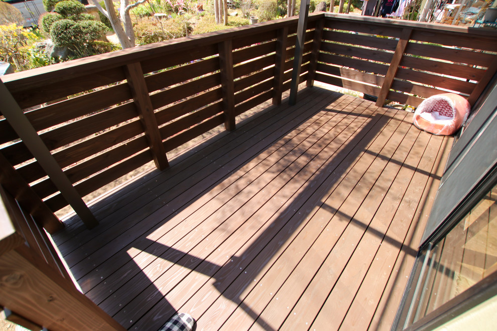This is an example of a ground level deck in Other with an awning and wood railing.