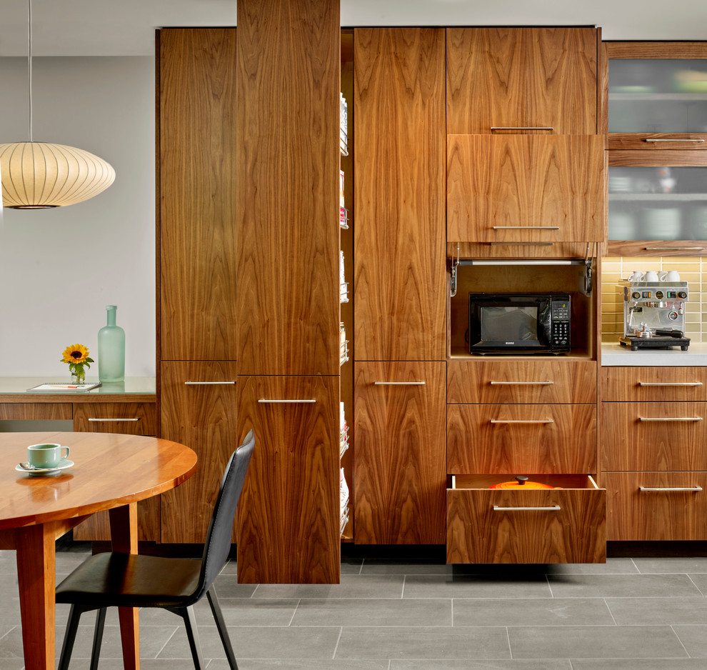Photo of a modern l-shaped open plan kitchen in San Francisco with flat-panel cabinets, medium wood cabinets, green splashback, subway tile splashback, stainless steel appliances, ceramic floors, with island, an undermount sink and concrete benchtops.