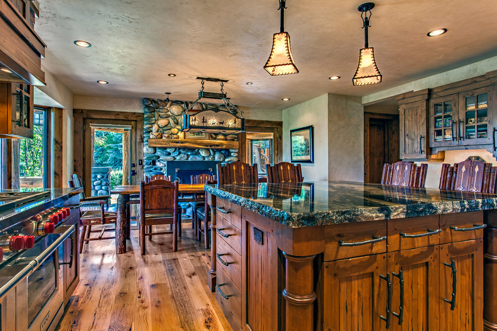 Kitchen/dining room combo - large rustic medium tone wood floor kitchen/dining room combo idea with a standard fireplace and a stone fireplace