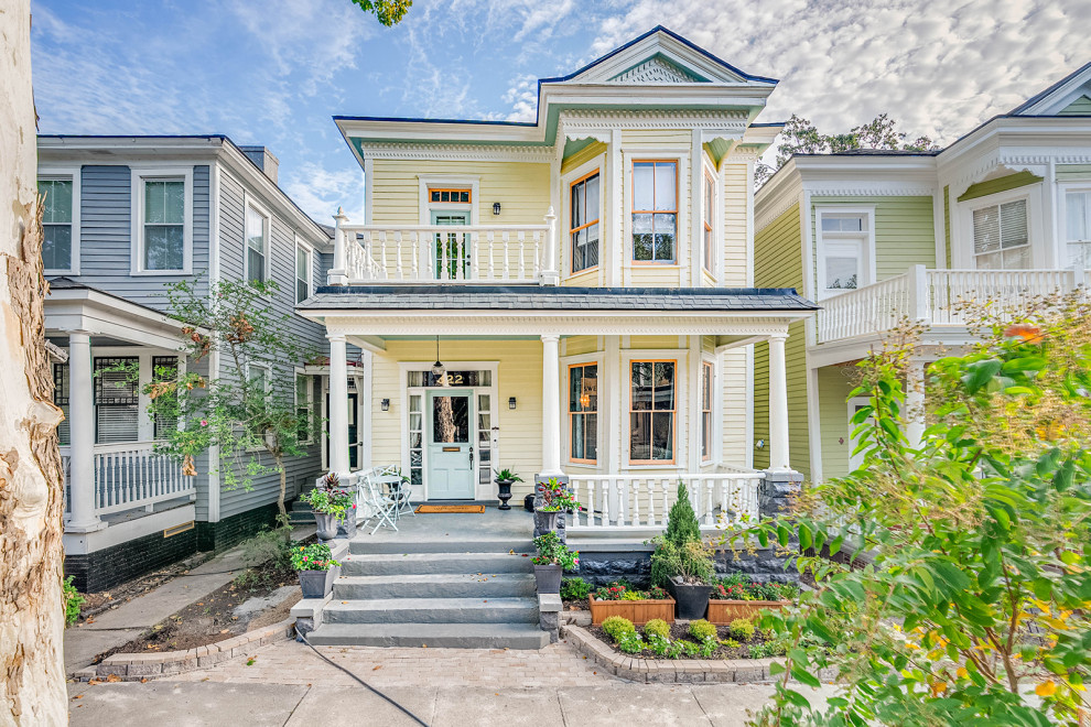 Large transitional yellow two-story wood and clapboard house exterior photo with a hip roof, a shingle roof and a gray roof