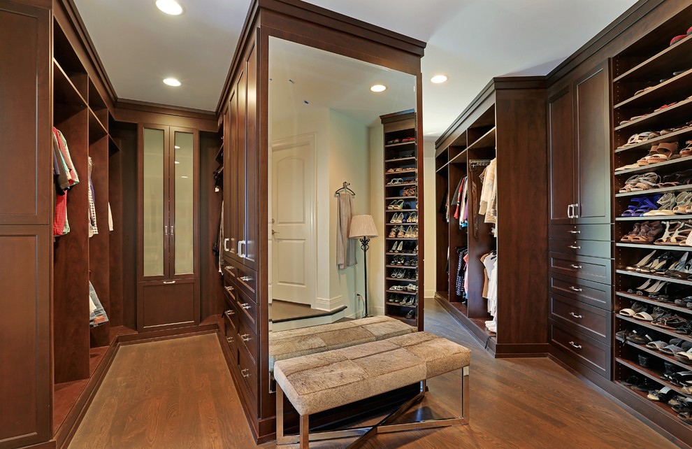 Design ideas for a large traditional gender-neutral walk-in wardrobe in Chicago with dark wood cabinets, medium hardwood floors and recessed-panel cabinets.