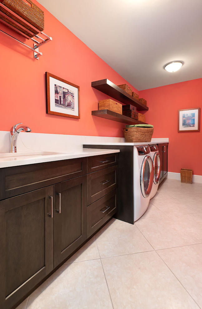 Einzeilige, Große Moderne Waschküche mit Unterbauwaschbecken, Schrankfronten im Shaker-Stil, dunklen Holzschränken, Marmor-Arbeitsplatte, oranger Wandfarbe, Marmorboden, Waschmaschine und Trockner nebeneinander, beigem Boden und weißer Arbeitsplatte in Miami